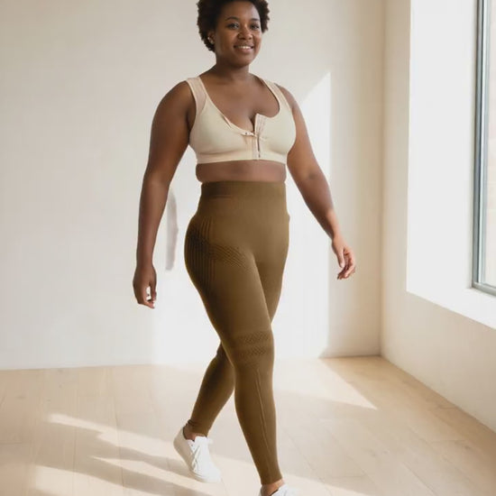 A woman walking slowly to the window in the beige bra and coffee leggings